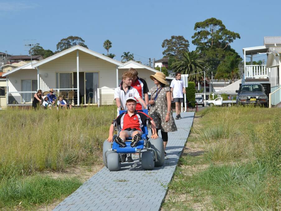 BEACH BOUND: Joshua Spruce heads down the wheelchair ramp in front of the Clyde View Holiday Park followed by Daniel Waplington and Natalie Bertosa.