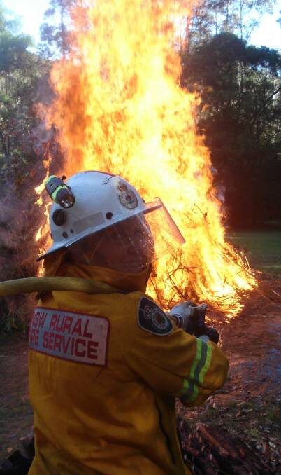 Narooma RFS brigade member Gillian Kearney oversees a pile burn. Fire permits are required from today in the Eurobodalla and Bega shires.