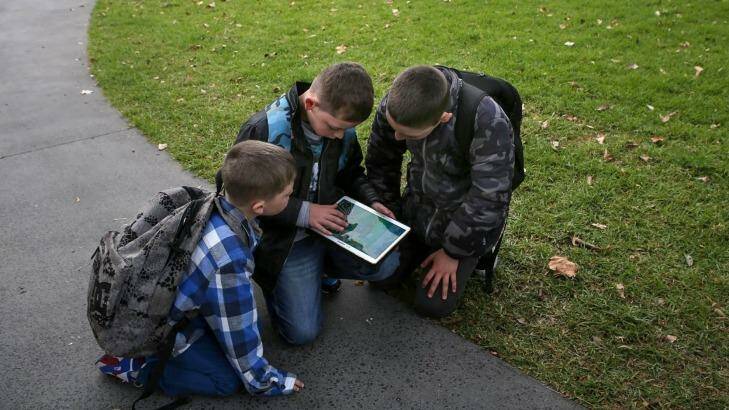 Pokemon enthusiasts - brothers Khodi, 7, Kheegan, 10, and Kaylen, 11 - capture Pokemons at Prince Alfred Park in Redfern with other enthusiasts. Photo: James Alcock