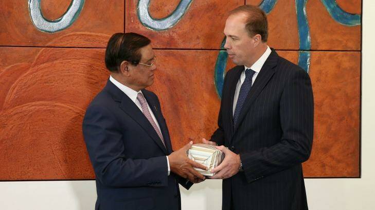 Immigration Minister Peter Dutton gives a present to Cambodian Deputy Prime Minister and Minister of the Interior Sar Kheng, during a signing of a memorandum of understanding. Photo: Alex Ellinghausen