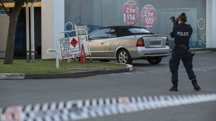 A forensic police officer takes photographs at the service station where the man says he was set free. Photo: Jessica Hromas