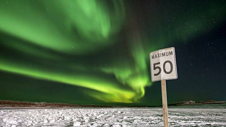 The northern lights illuminate the night sky above a road sign in Inuvik, Northwest Territories, Canada. Photo: NYT