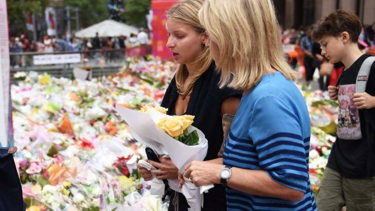Madeleine Pulver, victim of the collar bomb incident, fights back tears before placing flowers near the scene of the Martin Place siege with her mother on Thursday. Photo: Nick Moir