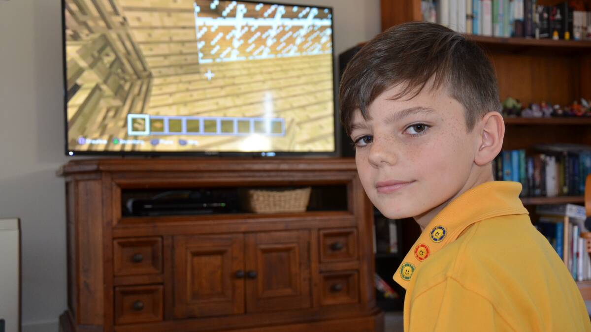 ALL MINE: Jacob Zimmermann indulging in Minecraft at his Malua Bay home.