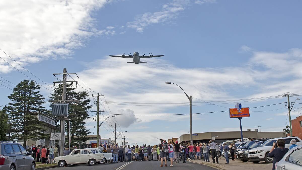 A RAAF C130 Hercules flies low over Bega's Carp St during the Anzac Day 2015 service. Photo: Kim Armstrong.