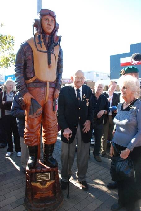 LIVING LEGEND:  Gus Winckel, a former First Lieutenant in the Netherlands East Indies Air Force, next to his carved likeness in front of the Air Raid Tavern.
