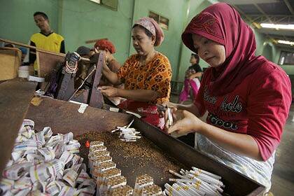 Hand made ... women work in pairs, rolling and cutting kretek cigarettes at a factory in Kudus. Each pair typically makes more than 5000 cigarettes each day.