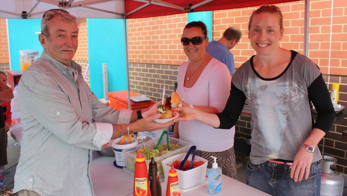 Leigh Hanlon collects his tasty hot potato and barbecue hamburger from Alyce Petts and Kate Whitton at the Tathra election day markets.