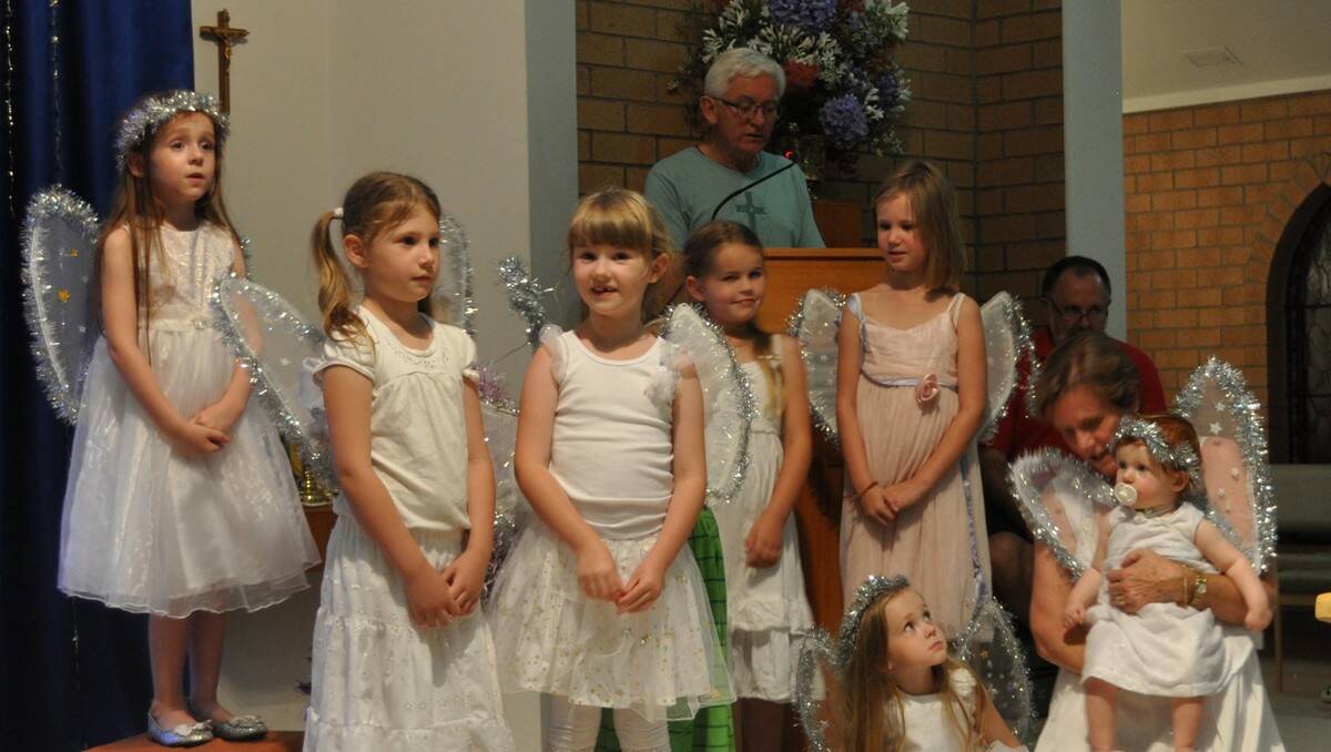 CHRISTMAS ANGELS: Kate Wallace, Lauren Smits, Angelica Ward, Finley Backo, Olivia Smits, Kay Walters, Anna Wallace and Jane Wallace in angelic pose while the Reverend Colin Walters narrates during the Batemans Bay Anglican Church of the Ascension’s Nativity service on Christmas Eve.