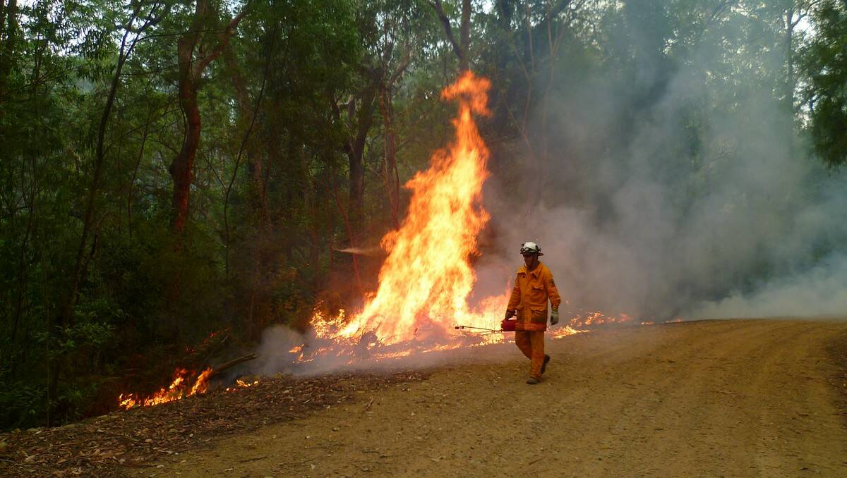 LINE OF FIRE: Malua Bay’s Mathew Makeham backburning at Jerrawangala on the weekend. The National Parks and Wildlife Service firefighter was one of many sent to the Deans Gap fire that threatened Sussex Inlet.