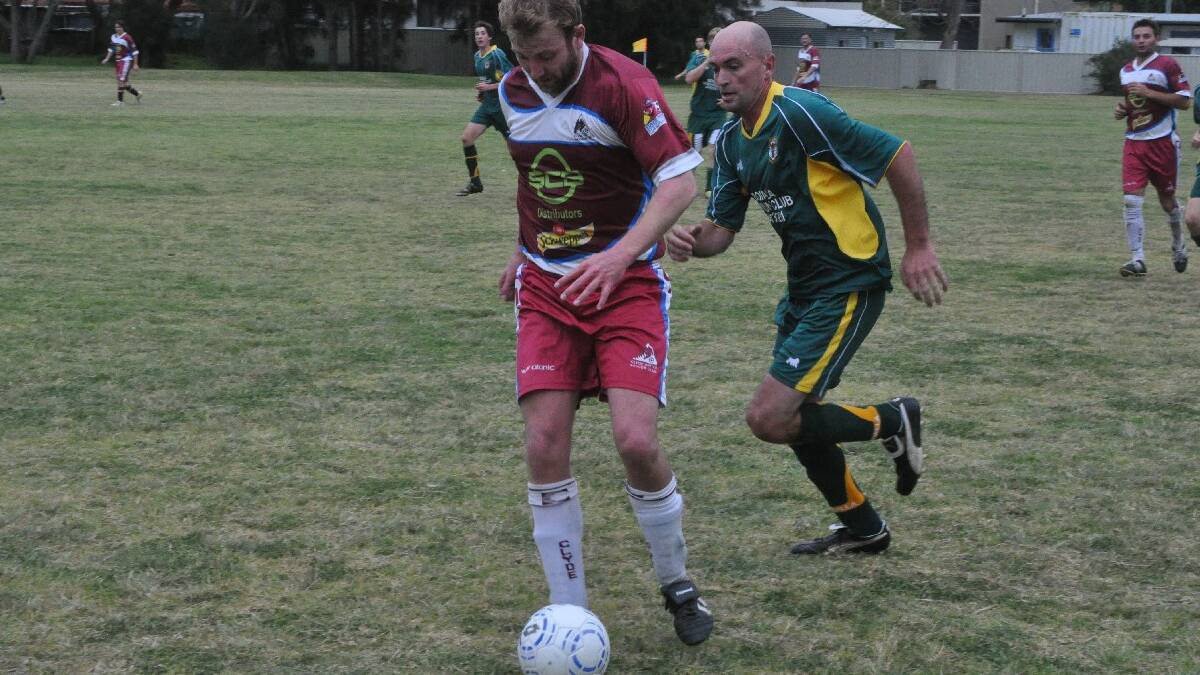 BATEMANS BAY: Bodalla's Paul Ferguson closes in on Clyde United's Neil Mackay during the EFA all age men's preliminary final on Sunday. 