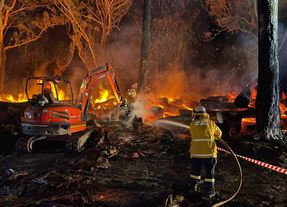 The brigades bring in machinery to try separate the logs. Photo: Batemans Bay RFS