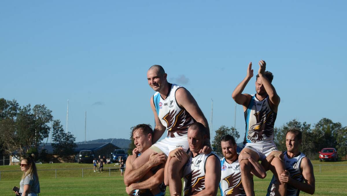 Michael Kenny (left) and Josh Visser are chaired off by teammates after playing in their 100th first-grade games with the Batemans Bay Seahawks.