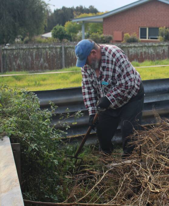 Volunteer John Lowe working hard to clear the land at the site of the new compost pile at the community garden.