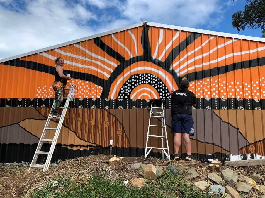 Beauty can spring from trauma: Bronwen Smith and Gavin Chatfield paint 'Rejuvenation' onto the side of a building at Mogo Wildlife Park