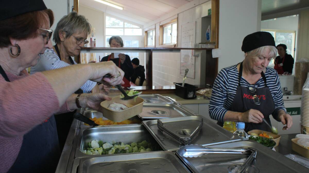 From left to right: Volunteers Robyn Bennett, Robin Scott-Charlton and Rhonda Noormets in the kitchen production line serving meals