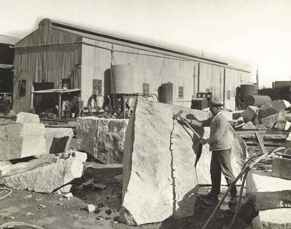 A worker using a plug and feather to split a granite boulder. Picture supplied.