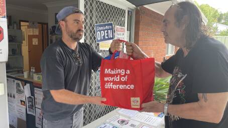 HELP: Shoalhaven Homeless Hub case worker Joey Winkler hands over a bag of food and other essentials to local man Ken Weir, who is living out of his car and a tent. Picture: Robert Crawford (file)