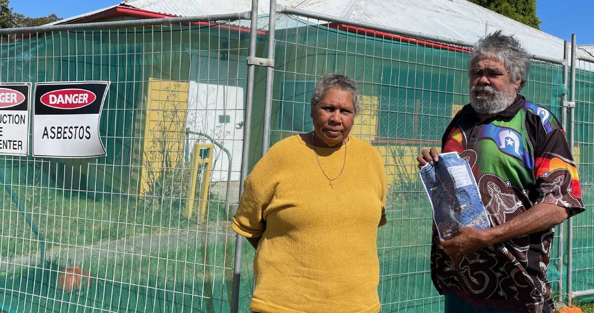 Deanna and Kenneth Campbell outside one of several asbestos-contaminated sites at their village on Wallaga Lake. This site has been fenced off but others have not. Mr Campbell is holding the map of the contaminated sites the EPA has identified. Picture by Marion Williams