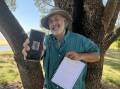 Enthusiastic Yowie researcher Wayne Lewin holding his phone with an image he had captured and a book of photographs. Picture by James Parker