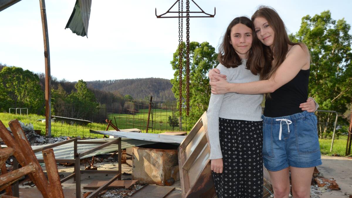 SISTERS: Ivy and Lilli Innes in the ruins of the family's Runnyford shed after rains greened up the paddocks. The historic homestead was saved from ember attack and grass fires.