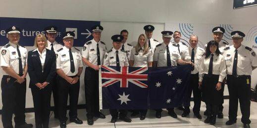 AIRBORNE ANGELS: Batemans Bay firefighters Tracey Anderson, second from left; Simon May, third from left; Ailish Pope, behind flag; and Nick Turner, to her right. The four are pictured before flying to Canada on July 19 with 11 other Rural Fire Service volunteers.