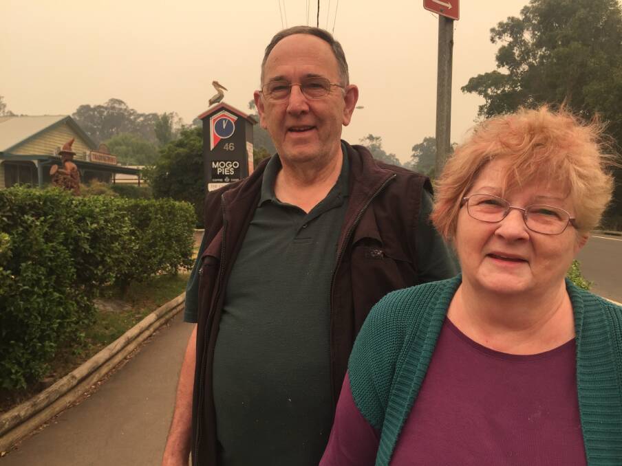 Barry and Teresa Horsburgh walk the main street of Mogo on New Year's Day grateful their patchwork business around the corner was saved but upset for the many who lost homes and workplaces.