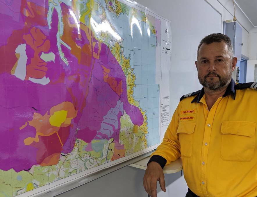 Batemans Bay RFS captain Ian Aitken in November, 2019, with a map showing how the 1994 fire could sweep through populated areas if repeated. It did on New Year's Eve.