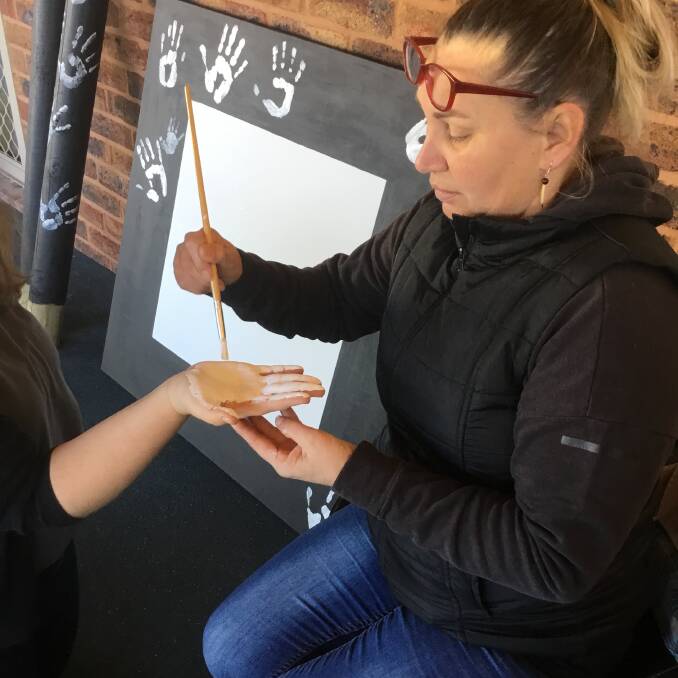 HAND IT TO HER: Artist Bronwen Smith helps prepare another handprint at the Muddy Puddles NAIDOC art session.