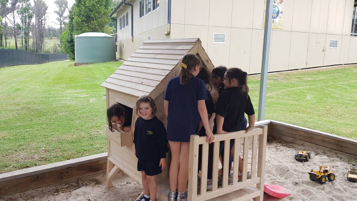Mogo Public School children playing in the completed cubby house, Scarlett Emerson-Smith pictured with the big smile.