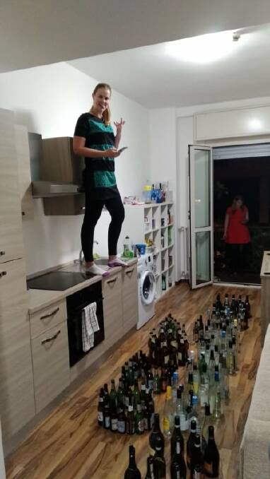 Raquel Brown takes a shot of their wine bottle display in the kitchen of her apartment. 