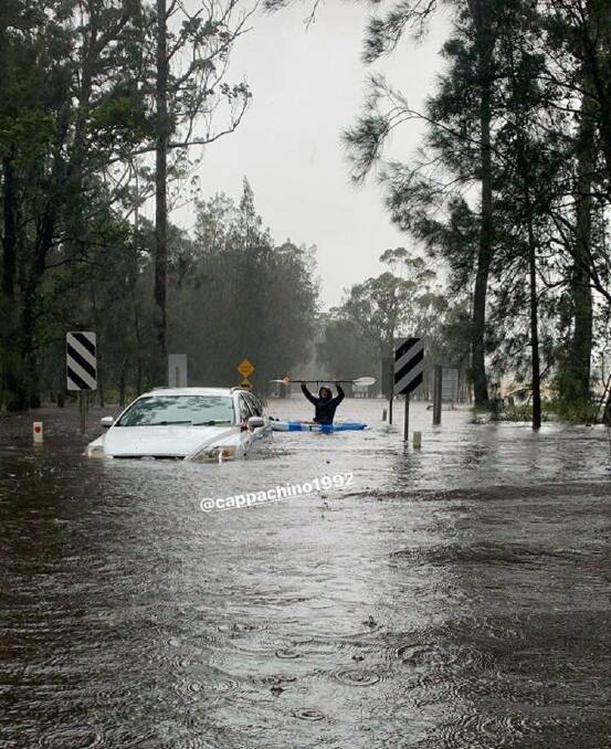 Kayakers paddle past the stranded car at Congo on Monday. 