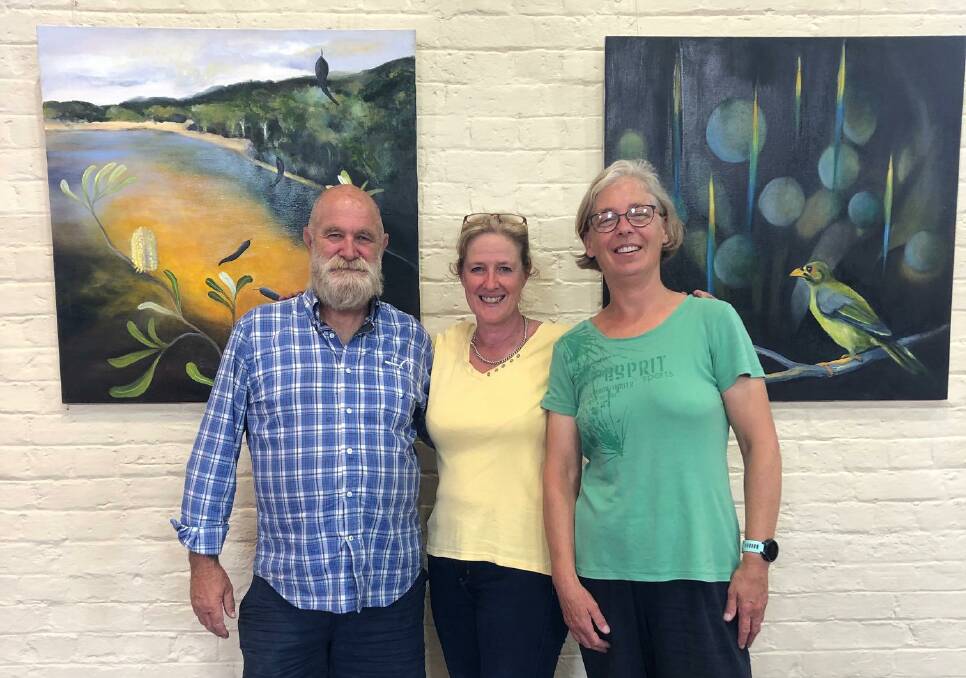 Geoffrey Odgers, Andrea Warren and Esther Workman hang works for the exhibition.
Paintings are Beyond the horizon and Rainforest bells. Both oil on canvas by artist Andrea Warren. Photo supplied
