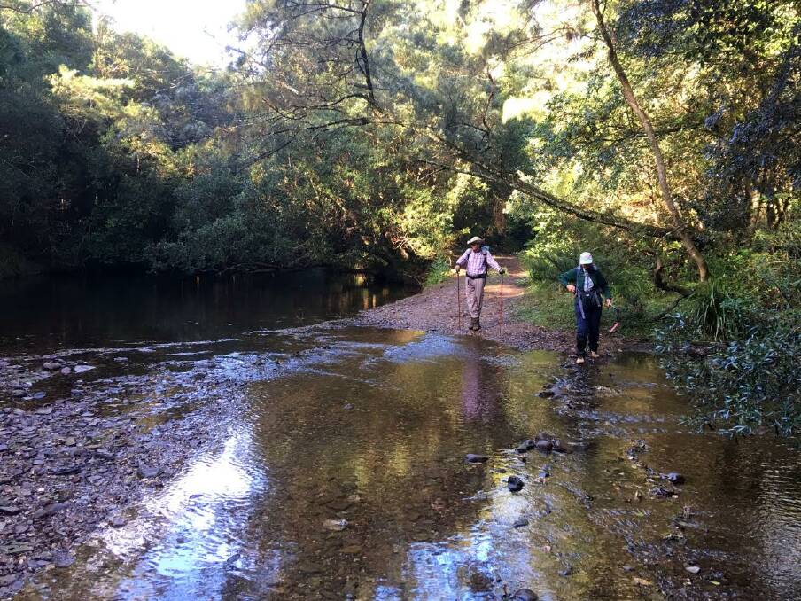 TAKE CARE: Rodney Hills and Mary Taylor avoiding wet feet as they cross Currowan Creek.