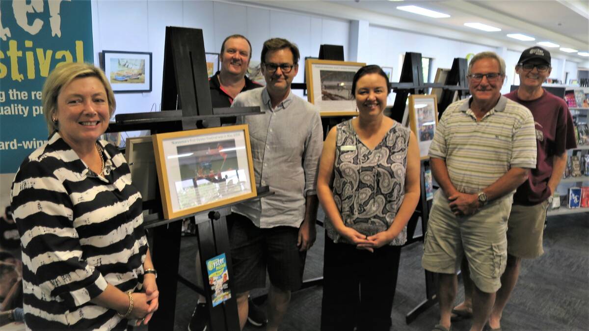 Oyster Festival chair Cath Peachey and Narooma Head Librarian Alice Johnson show the Story of the Narooma Oyster Festival to some of the Festival board members Michael Gardner, Niels Bendixsen, David Maidment and Lindsay Brown.