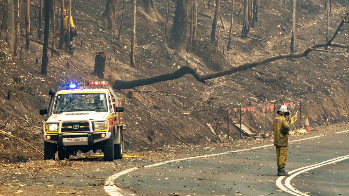 Fire crews work to remove dangerous burned trees along the Princes Highway. The NSW Rural Fire Service said that falling trees were a major concern on Thursday. Picture: Sitthixay Ditthavong