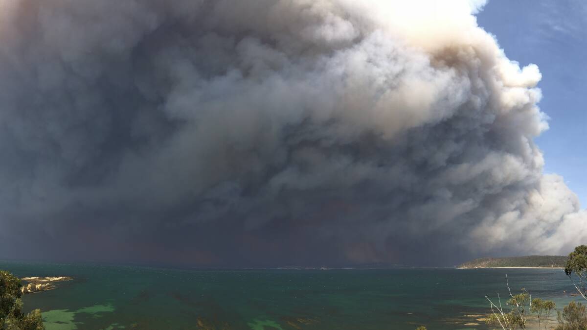 A photo taken from Longbeach clifftop, looking back towards the bay on Tuesday morning. Flaming debris is falling from the smoke cloud. Picture: David Shearer