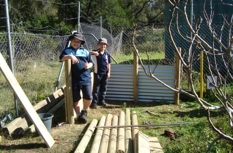Farmyard work: St Bernard’s Primary School students Riley Sommerville and Joshua Sawyer give their seal of approval to progress on the sheep shelter they were helping to build with members of Batemans Bay Men's Shed.
