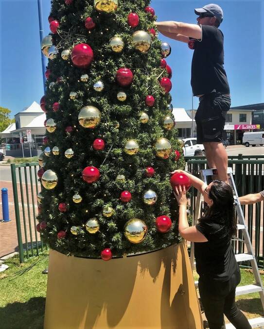 Batemans Bay Business and Tourism Chamber secretary Rebecca Mahon and Troy Mahon prepare the Christmas tree in Batemans Bay.