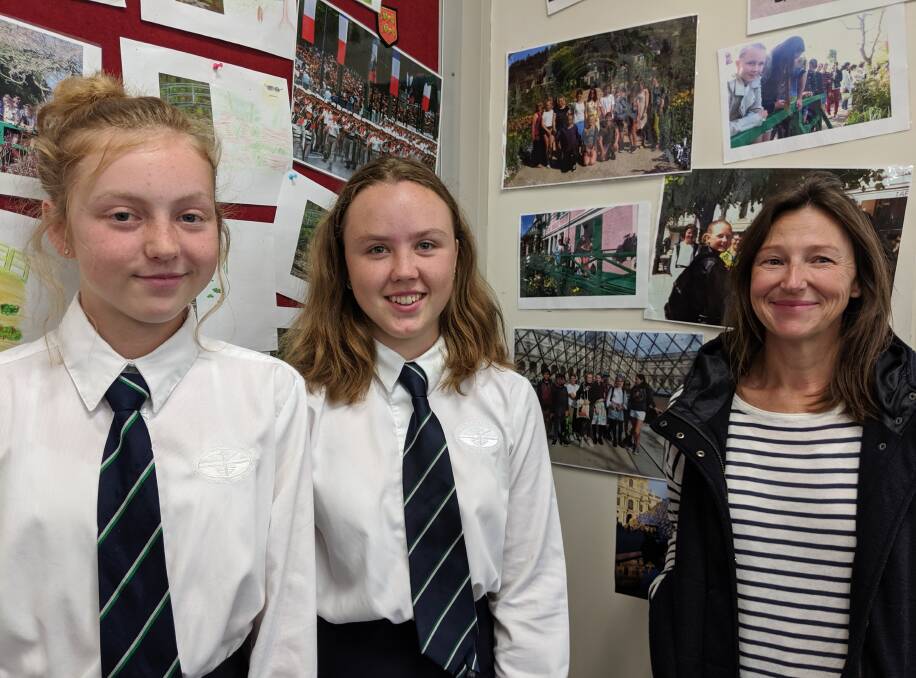 FRANCOPHONES: Students Maddie Jones and Jane Wicks with French teacher Kate Woolnough stand next to photos of the school's previous trips to France.