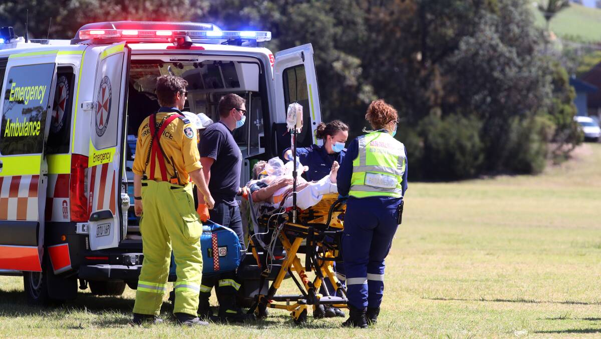 A patient is transported from an ambulance to a waiting NSW Ambulance helicopter.