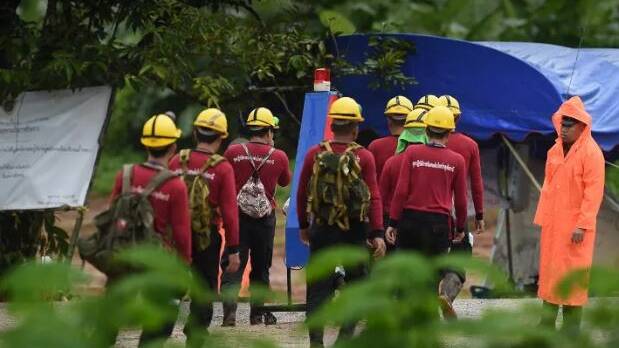 Rescue workers walk up a road towards Tham Luang cave on Tuesday. Photo: Kate Geraghty