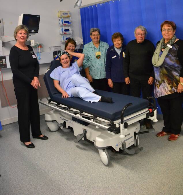 BEDDING IN: Marie Loudon, Maxine Schumacher, Lisa Wilson, Jeanette Sinclair, Jacki Harding, David Wallace and Ann McClintock demonstrate the new trolley the Lions Club purchased for Batemans Bay Hospital. 