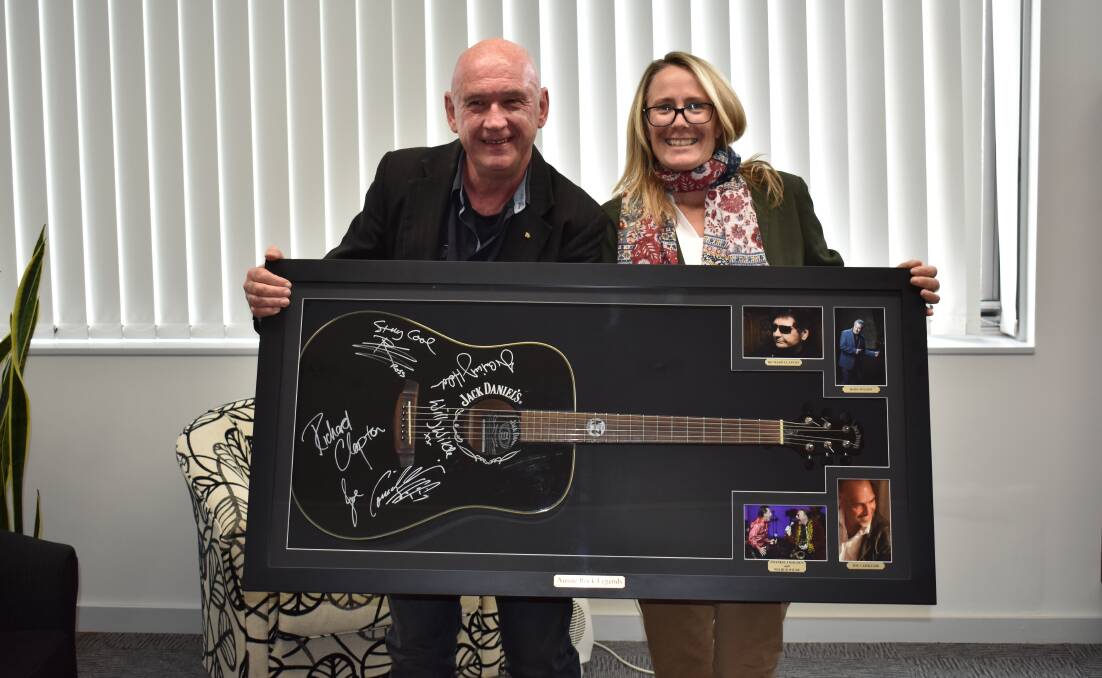 GIVE BACK: David White and mayor Liz Innes with the major rain dance raffle prize - one-of-a-kind Jack Daniel’s signed acoustic guitar.
